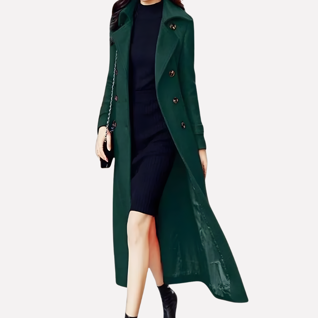 Women's long green double-breasted trench coat styled over a dark dress and black boots.